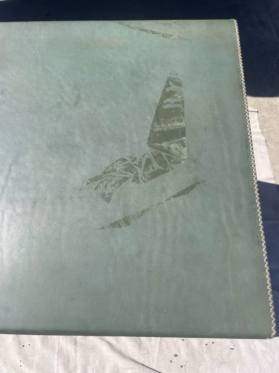 Green leather-covered chest with scuffed, damaged finish on the top, before restoration